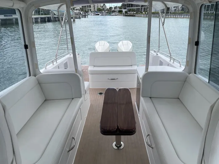  Yacht Photos Pics 2023 MJM 35z boat interior with white seating and wooden table, overlooking calm waters.