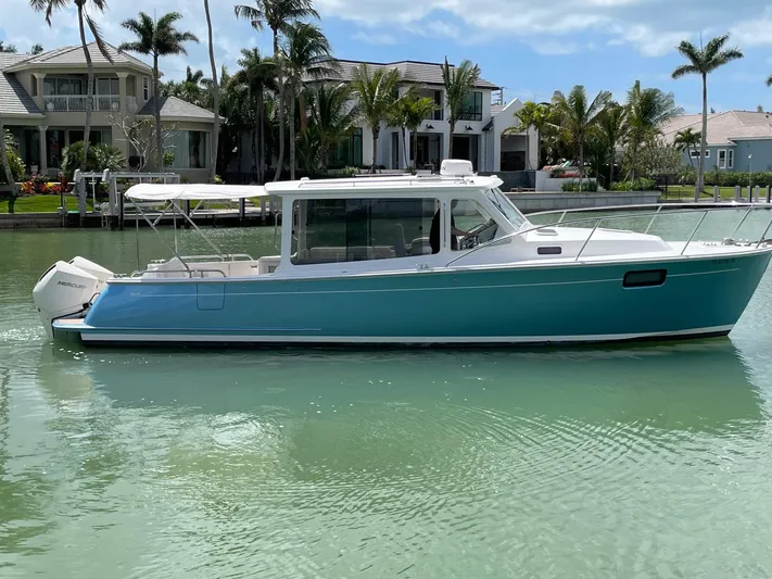  Yacht Photos Pics 2023 MJM 35z boat on calm water, with luxury homes and palm trees in the background.