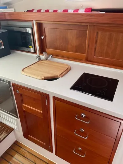  Yacht Photos Pics 2023 MJM 35z yacht kitchen with wooden cabinetry, sink, and stovetop.