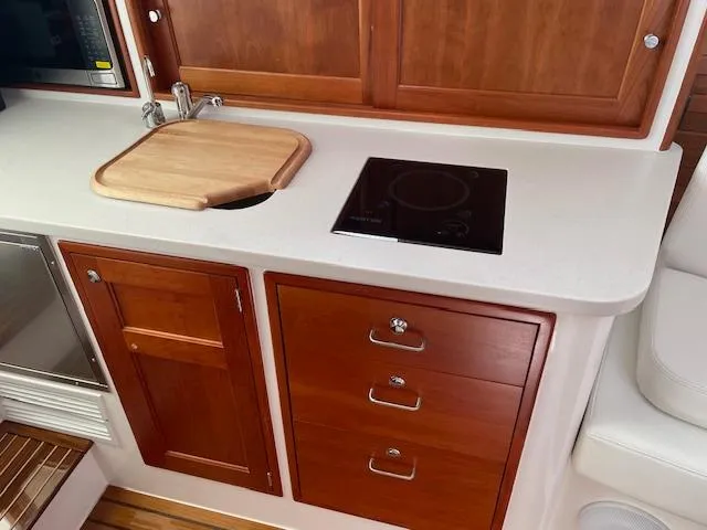  Yacht Photos Pics 2023 MJM 35z yacht interior with wooden cabinetry, sink, and stovetop.