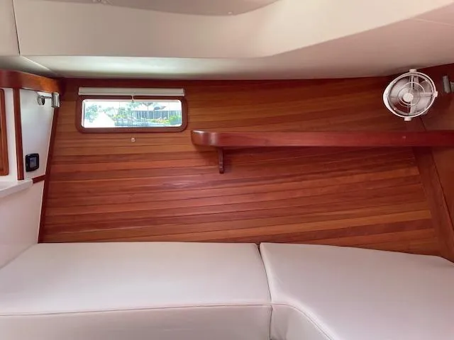  Yacht Photos Pics 2023 MJM 35z boat interior with wooden paneling, cushioned seating, and a small window.