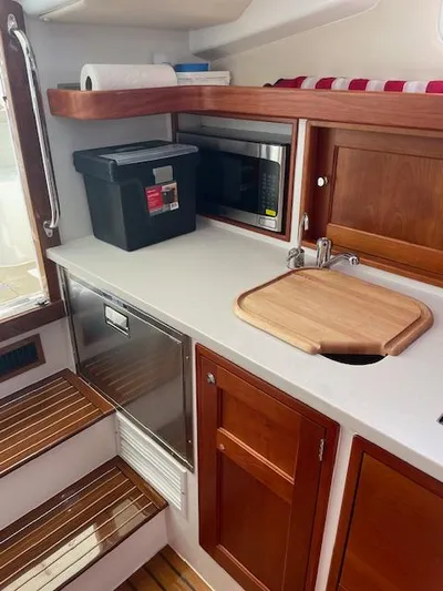  Yacht Photos Pics 2023 MJM 35z yacht kitchen with wooden cabinets, microwave, and cutting board.