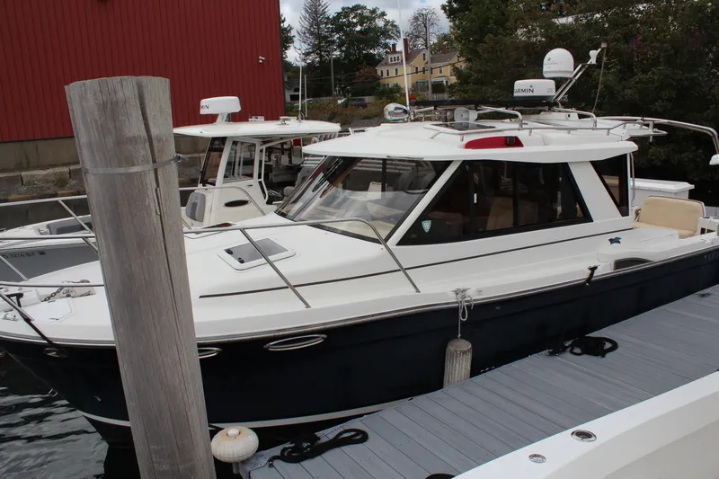 Shake N Bake Yacht Photos Pics 2013 Cutwater 28 LE boat docked near a red building, surrounded by trees.