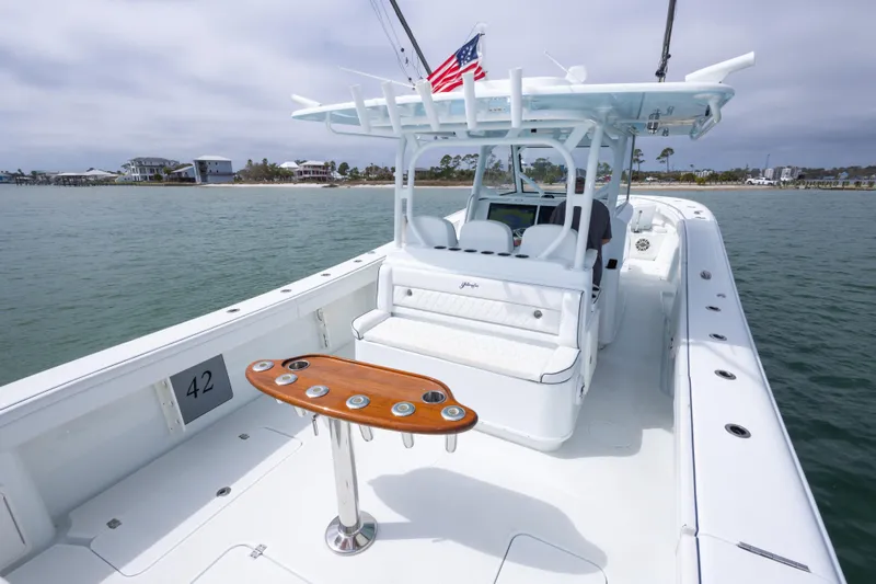  Yacht Photos Pics 2020 Yellowfin 42 Offshore boat with sleek design, cruising near coastal homes.
