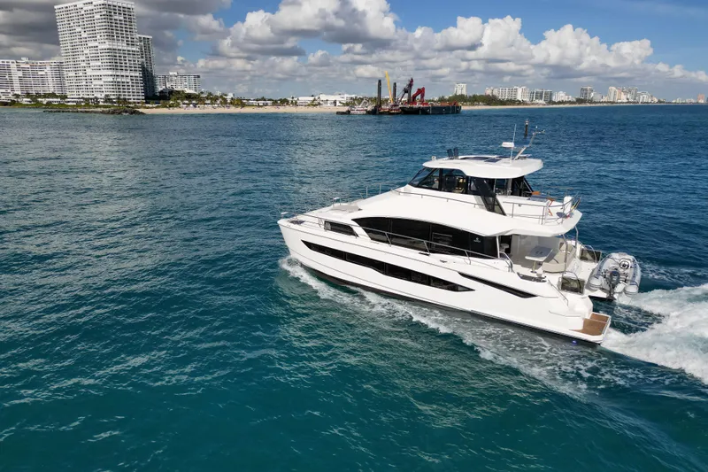  Yacht Photos Pics Aquila 54 Yacht 2025 cruising near a coastal city under a partly cloudy sky.