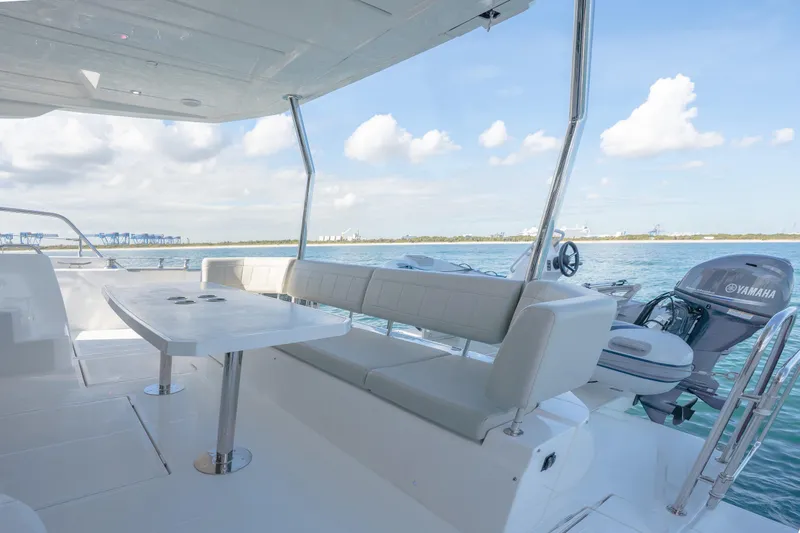  Yacht Photos Pics Luxurious 2025 Aquila 54 Yacht deck with seating, table, and Yamaha engine, overlooking serene waters.