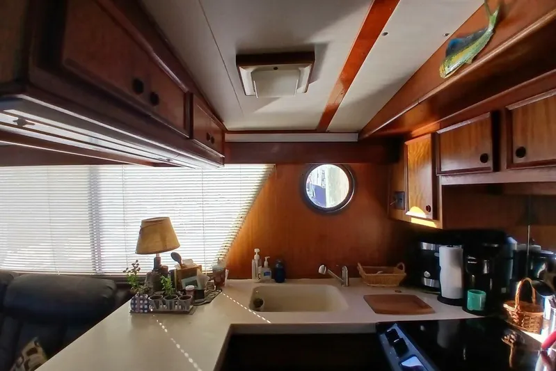Concrete Idea Yacht Photos Pics Interior of 1977 Hatteras 48 Long Range Cruiser kitchen with wooden cabinets and porthole window.