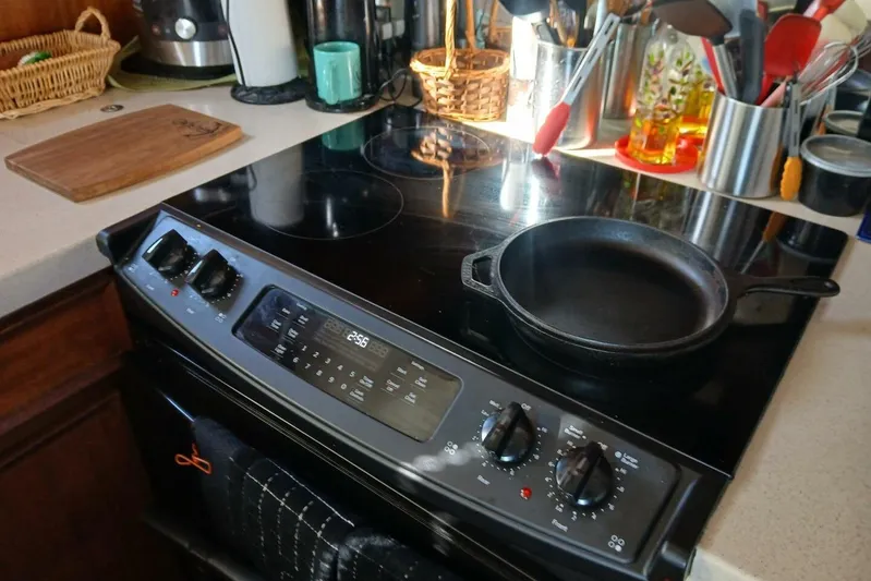 Concrete Idea Yacht Photos Pics Modern kitchen stove with cast iron skillet, surrounded by utensils and cutting board.