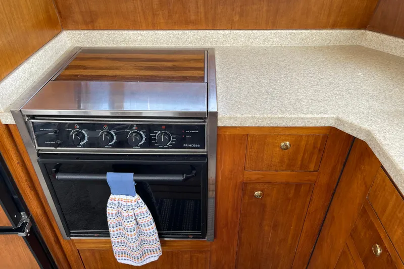  Yacht Photos Pics 2000 Mainship 390 Trawler kitchen with stove, wooden cabinets, and countertop.