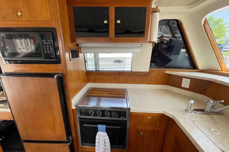  Yacht Photos Pics 2000 Mainship 390 Trawler kitchen with wood cabinetry, stove, microwave, and countertop.