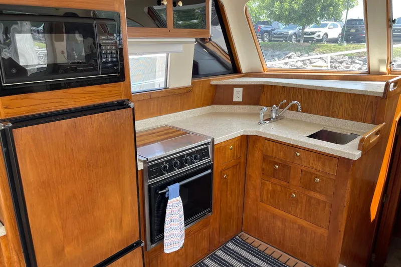  Yacht Photos Pics Kitchen area of 2000 Mainship 390 Trawler with wood cabinetry and modern appliances.
