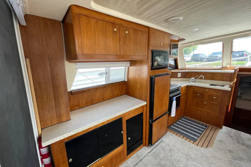  Yacht Photos Pics Interior of 2000 Mainship 390 Trawler with wooden cabinetry and compact kitchen area.