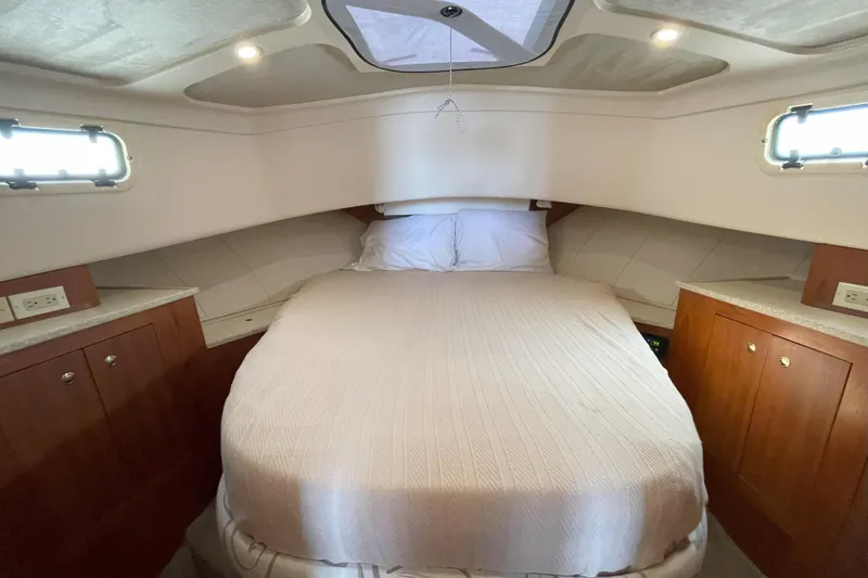  Yacht Photos Pics Cozy bedroom in 2000 Mainship 390 Trawler with wood cabinets and overhead lighting.