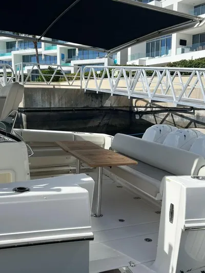 Bite Me Yacht Photos Pics 2017 Boston Whaler 420 Outrage boat with seating and table, docked near modern buildings.