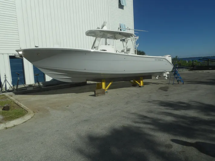  Yacht Photos Pics 2020 Cobia 320 Center Console boat on stands, near a white building, under clear blue sky.