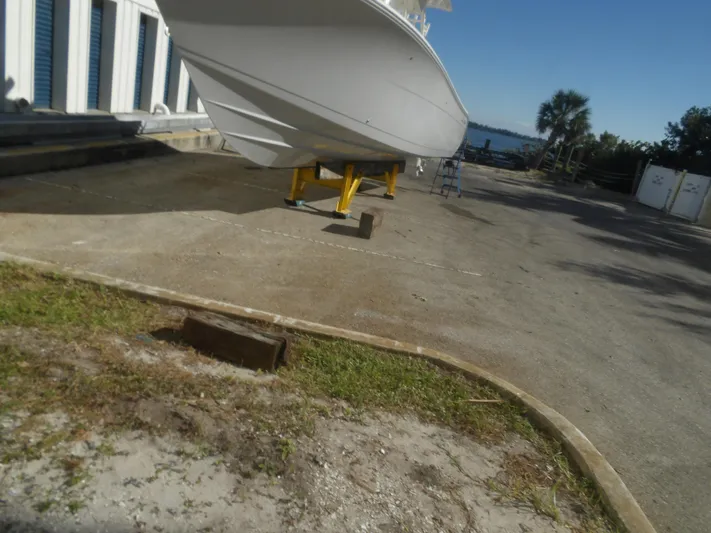  Yacht Photos Pics 2020 Cobia 320 Center Console boat on stands, near waterfront storage area.