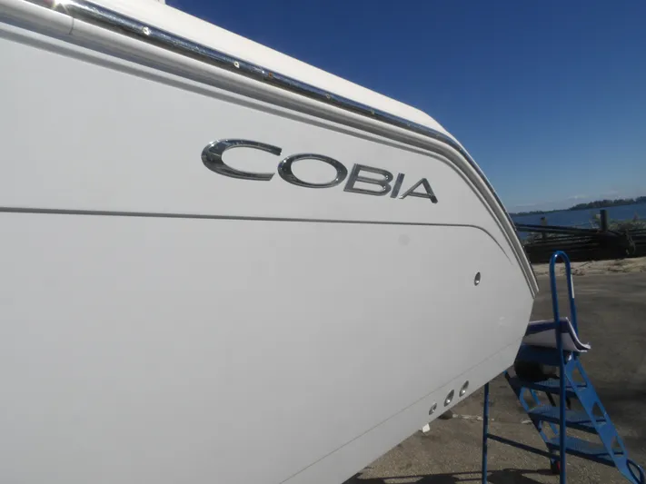  Yacht Photos Pics 2020 Cobia 320 Center Console boat side view with logo, docked near water.
