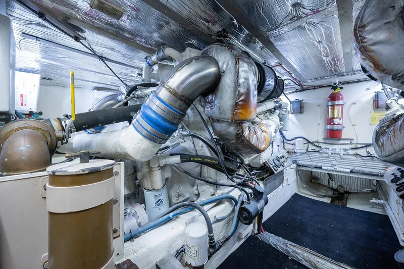 Motivated Seller Yacht Photos Pics Engine room of a 1986 Tollycraft Pilothouse yacht with visible machinery and fire extinguisher.