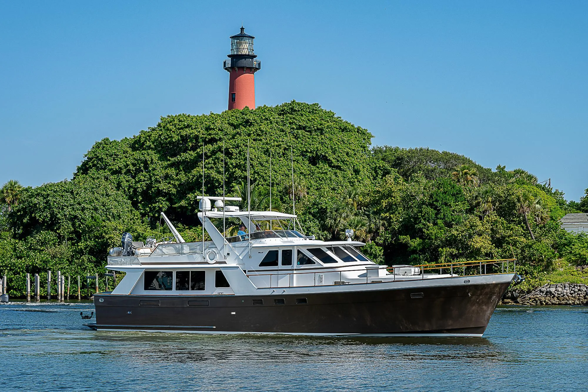 1986 Tollycraft Pilothouse yacht cruising near a lighthouse.