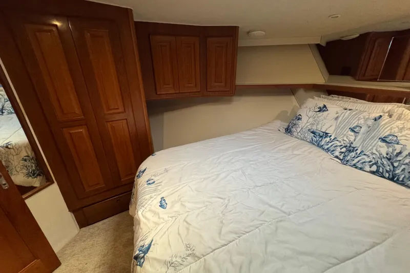  Yacht Photos Pics Cozy bedroom in 1995 Viking 58 Convertible yacht with wooden cabinets and nautical-themed bedding.