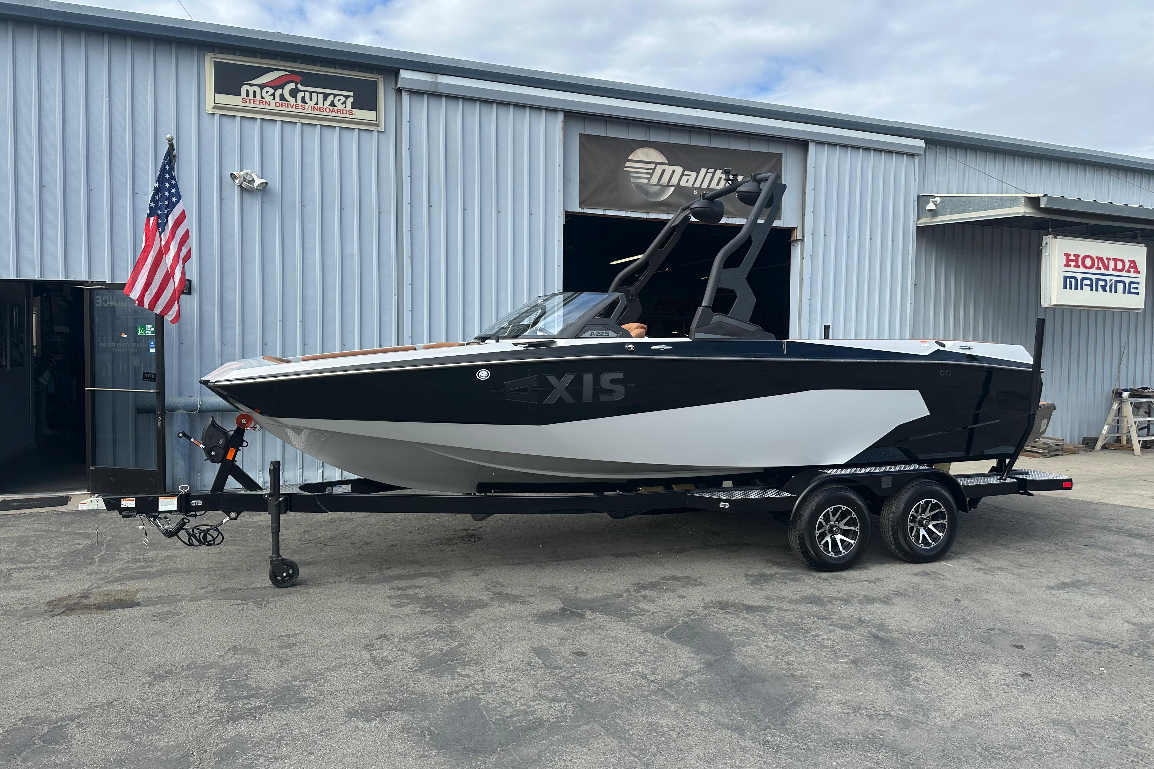 2026 Axis A225 boat on trailer outside marine dealership with American flag.