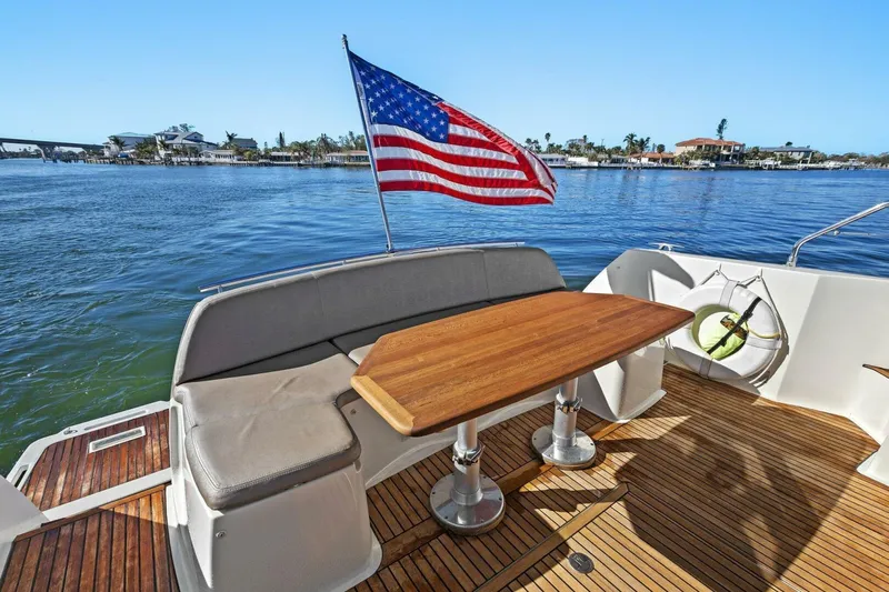 Slainte Yacht Photos Pics Prestige 450 S yacht deck with American flag, wooden table, and waterfront view.