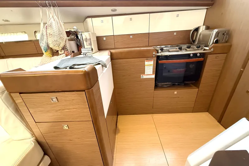 Cruzeiro Do Sul Yacht Photos Pics Interior of 2013 Jeanneau Sun Odyssey 44 DS yacht kitchen with wood cabinetry and appliances.