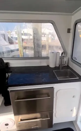 "silver Lining" Yacht Photos Pics Compact boat kitchen with stainless steel drawers, sink, and paper towels, featuring a window view.