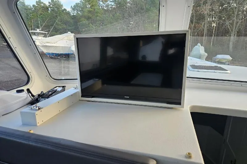 "silver Lining" Yacht Photos Pics Boat interior with a mounted TV, surrounded by windows and outdoor view.