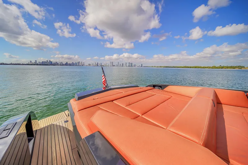  Yacht Photos Pics Luxury Vanquish VQ58 yacht with orange seating, ocean view, and city skyline in the background.