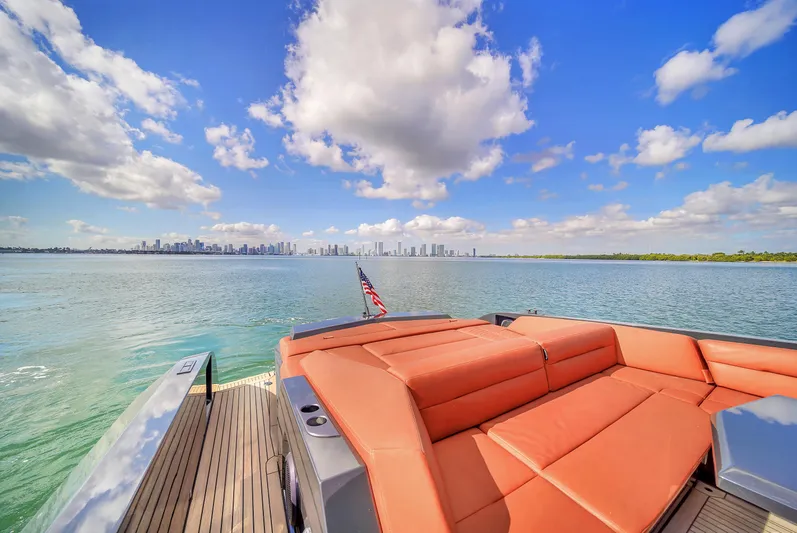  Yacht Photos Pics Luxury Vanquish VQ58 yacht with orange seating, ocean view, and city skyline in the background.