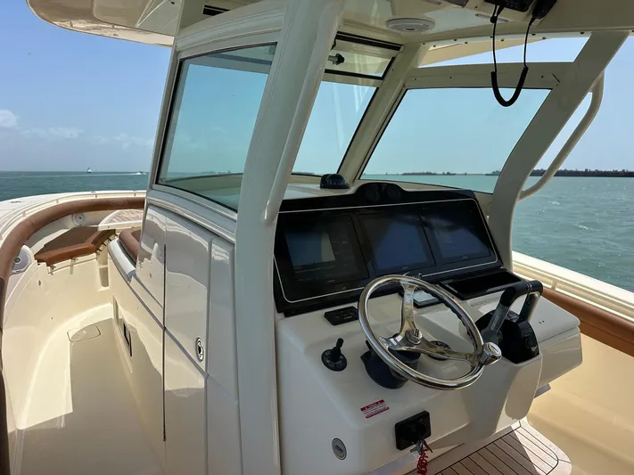  Yacht Photos Pics 2015 Scout 350 LXF boat helm with steering wheel and navigation screens, on open water.