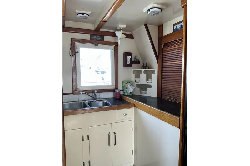  Yacht Photos Pics 2009 Hugh Huff Custom Pilothouse Trawler kitchen with sink, window, and wooden cabinetry.
