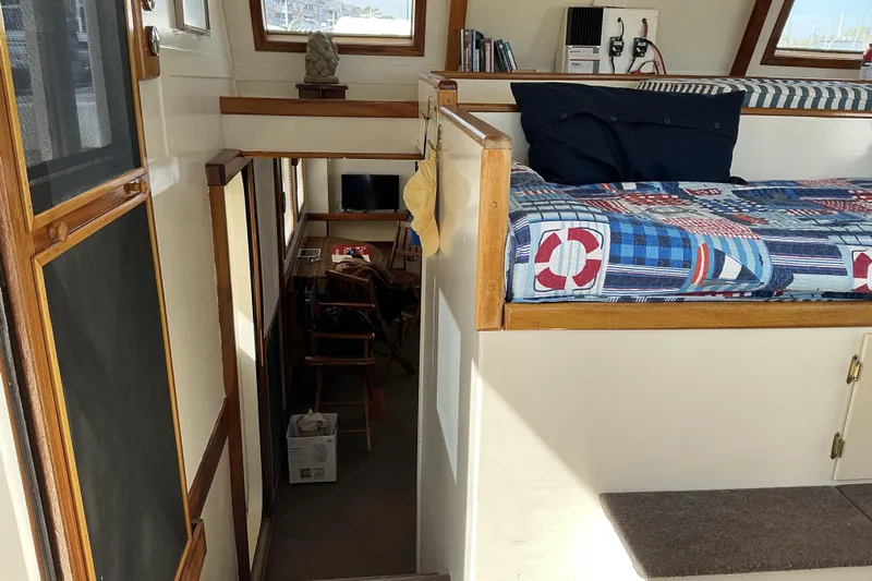  Yacht Photos Pics Interior of 2009 Hugh Huff Custom Pilothouse Trawler with nautical-themed bedding and cozy seating area.