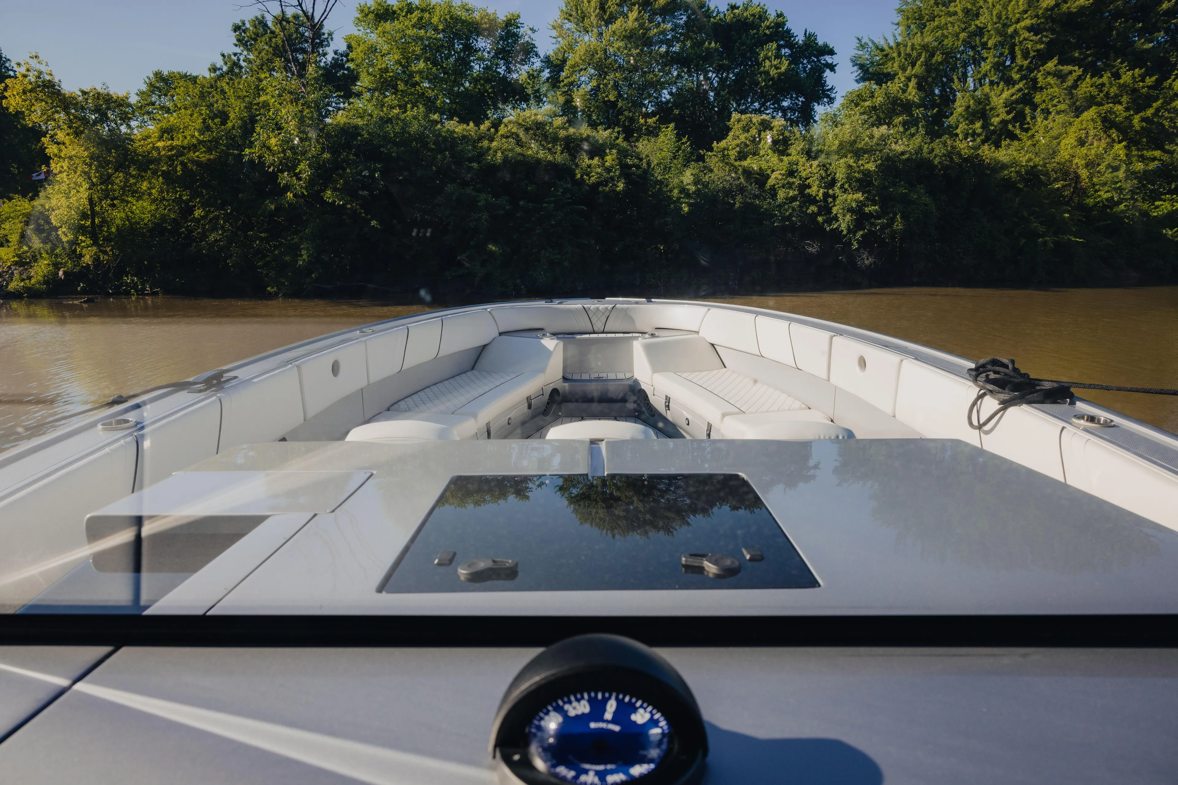  Yacht Photos Pics 2021 Midnight Express 43 Open boat on calm river, surrounded by lush greenery.