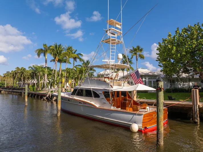 Ta-boo Yacht Photos Pics 1970 Rybovich 54 yacht docked by palm trees under a clear blue sky.