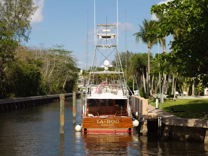 Ta-boo Yacht Photos Pics 1970 Rybovich 54 yacht docked in a lush, tropical canal setting.
