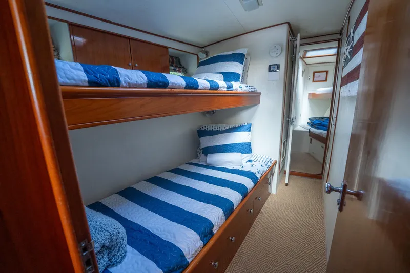 Ta-boo Yacht Photos Pics 1970 Rybovich 54 yacht cabin with striped bedding and wooden bunk beds.