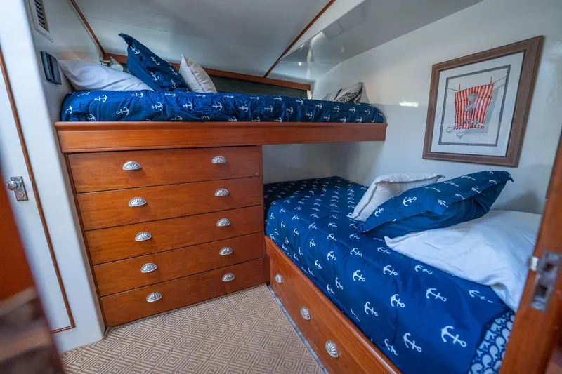 Ta-boo Yacht Photos Pics Interior of 1970 Rybovich 54 yacht with wooden bunk beds and nautical-themed bedding.