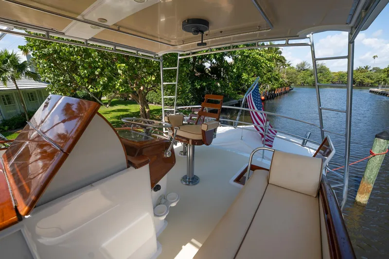 Ta-boo Yacht Photos Pics 1970 Rybovich 54 yacht deck with seating, helm, and American flag by a scenic river.