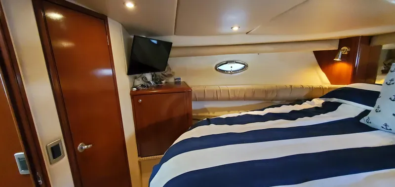 Chelarious Yacht Photos Pics Interior of 2005 Meridian 411 Sedan yacht with striped bedding and wall-mounted TV.