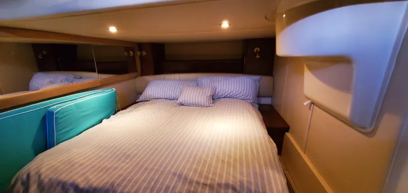 Chelarious Yacht Photos Pics Cozy bedroom in 2005 Meridian 411 Sedan yacht with striped bedding and ambient lighting.