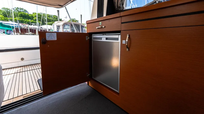  Yacht Photos Pics 2018 Jeanneau NC11 interior with open cabinet revealing a compact refrigerator.