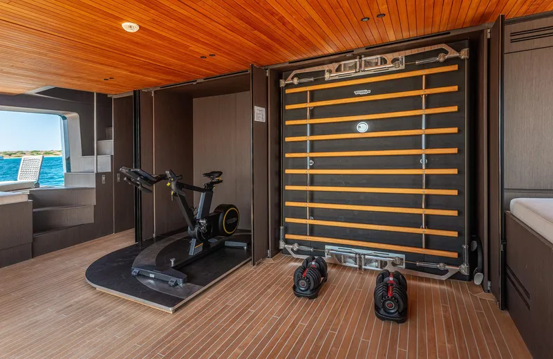 Just Marie 3 Yacht Photos Pics Luxury yacht Sanlorenzo SX112 2021 gym with exercise bike and weights, wooden interior.