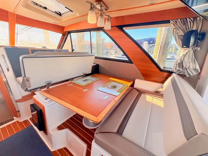 Reliance Yacht Photos Pics Interior of 2023 Cutwater 32 Coupe with wooden table and seating area.