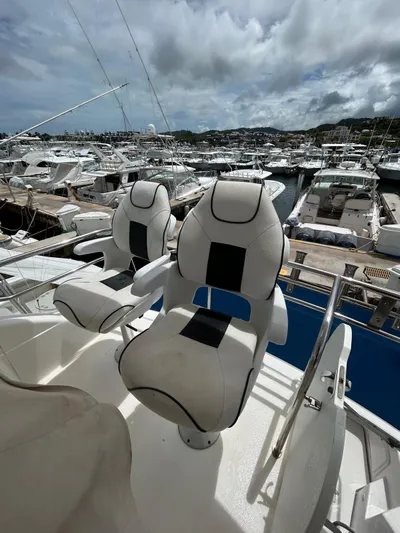  Yacht Photos Pics Two white captain chairs on a 2005 Riviera 37 Flybridge yacht, docked at a marina.