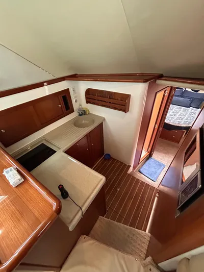  Yacht Photos Pics 2005 Riviera 37 Flybridge yacht interior with kitchenette and wooden flooring.