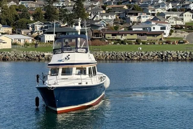 Ocean Baron Yacht Photos Pics 2001 Sabreline Sedan boat cruising near a coastal residential area.