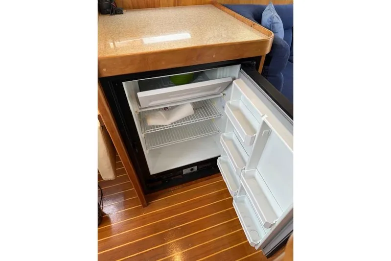 Ocean Baron Yacht Photos Pics Open mini fridge in 2001 Sabreline Sedan, wooden floor, countertop above.