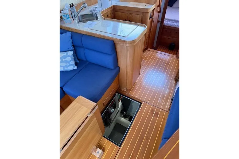 Ocean Baron Yacht Photos Pics 2001 Sabreline Sedan interior with blue seating, wooden flooring, and open engine hatch.